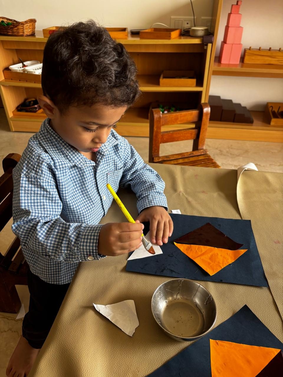 Child painting paper triangles at the art table