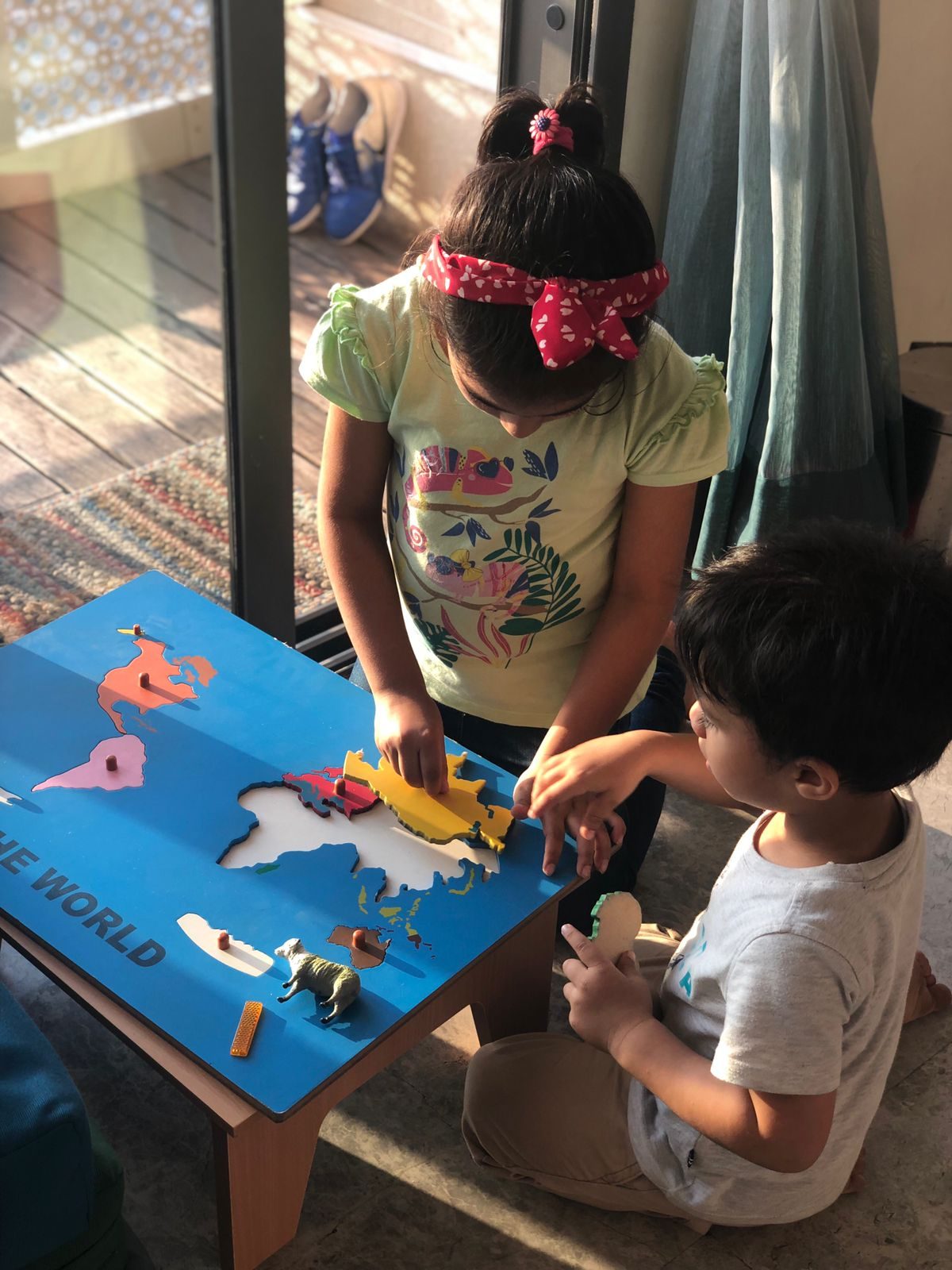 Children exploring continents on a world map puzzle