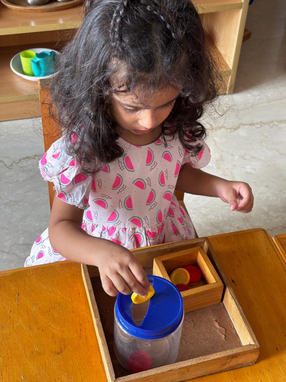 Child concentrating on a coin-posting practical life activity