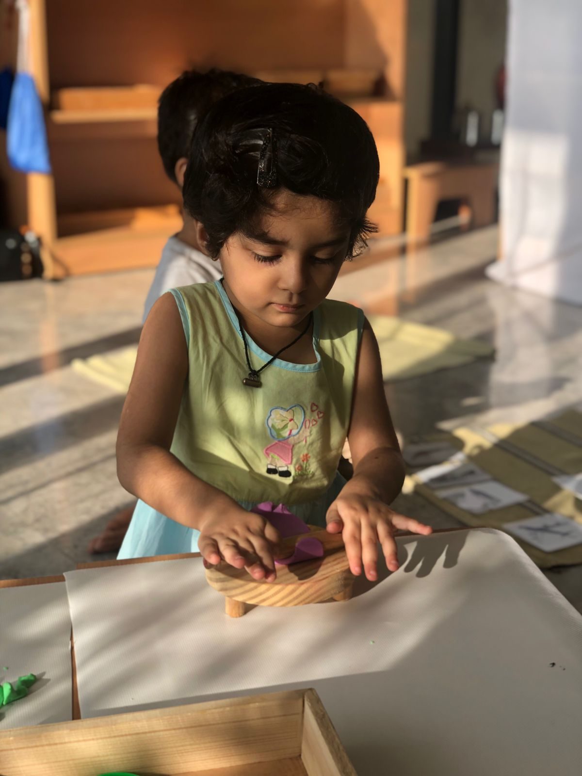 Child rolling playdough with a wooden roller